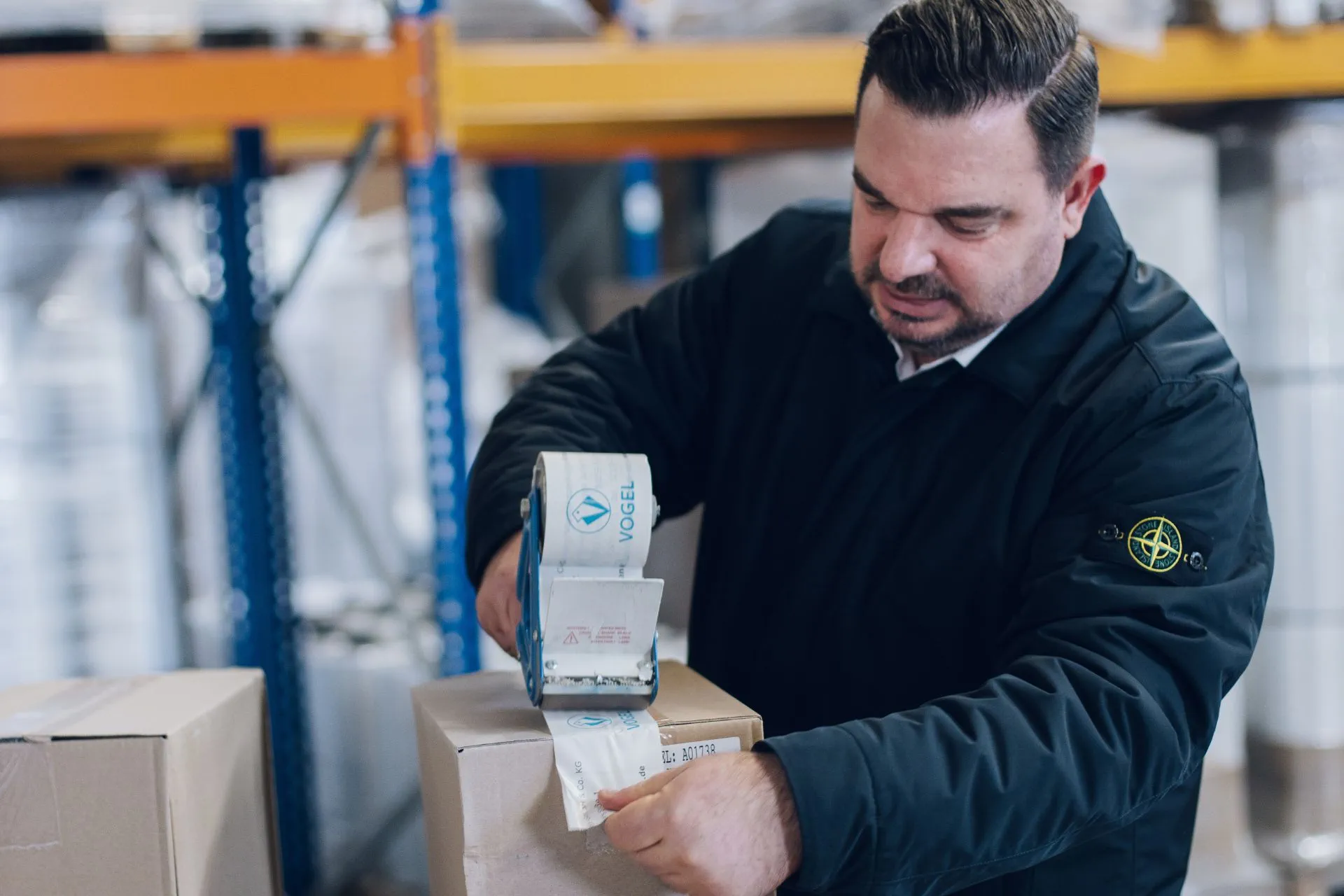 Ein Mitarbeiter von Vogel Verpackungen verschließt händisch einen Karton